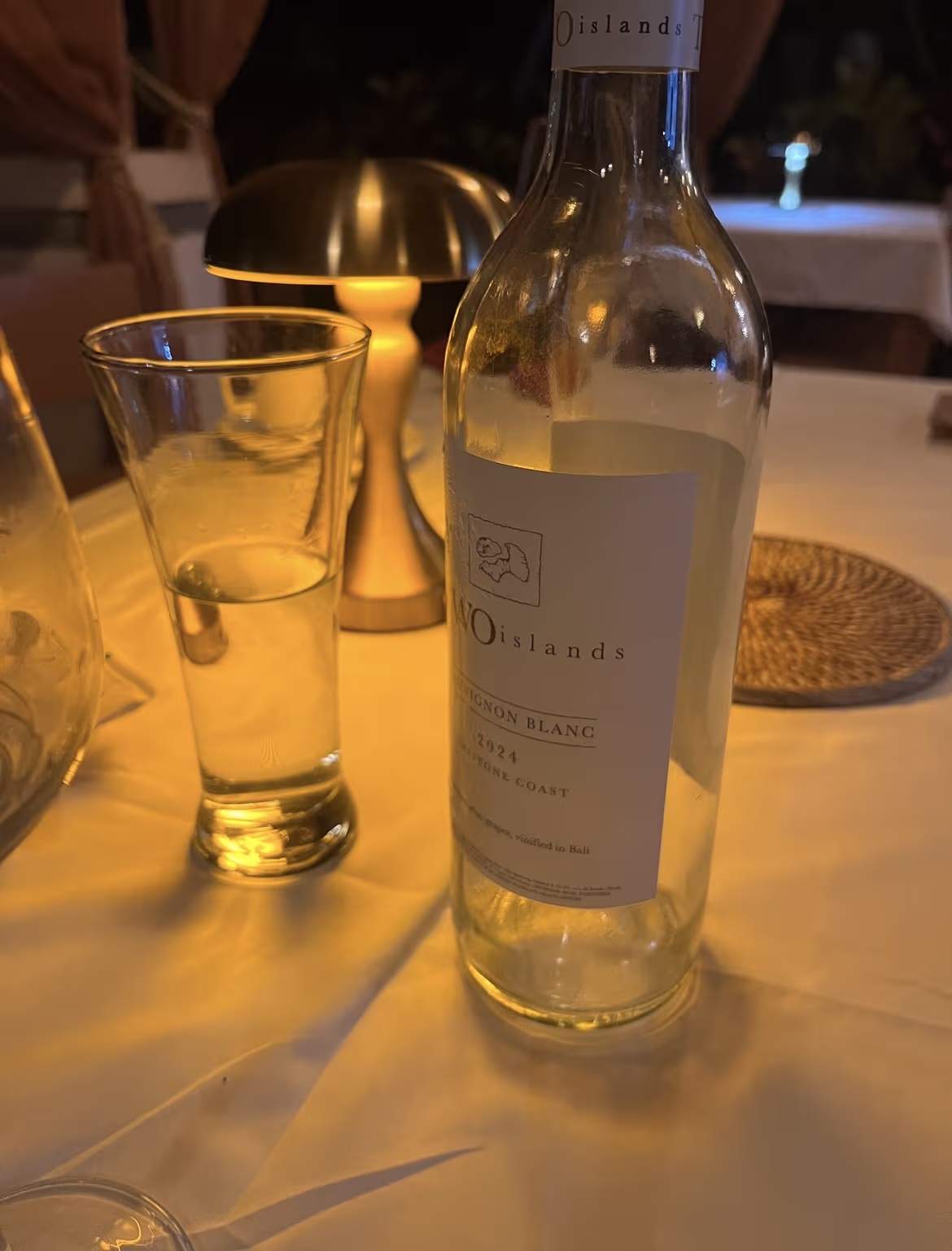 White wine bottle and glass on a warmly lit table at Kavana Penida